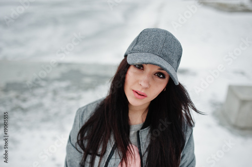 Stylish brunette girl in gray cap, casual street style on winter day.