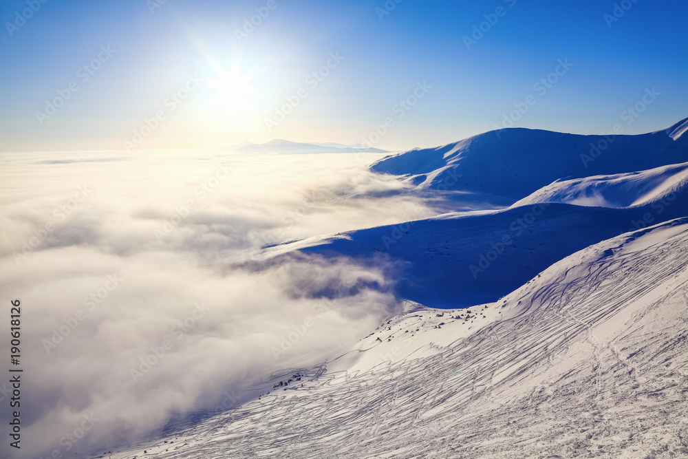 Fantastic scenery with the high mountains in snow, dense textured fog  in the cold winter day.