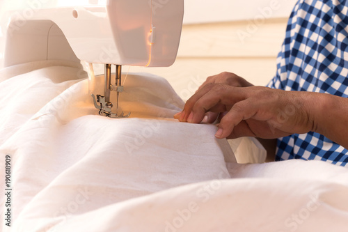 Woman's hands sewing linen cotton with sewing machine