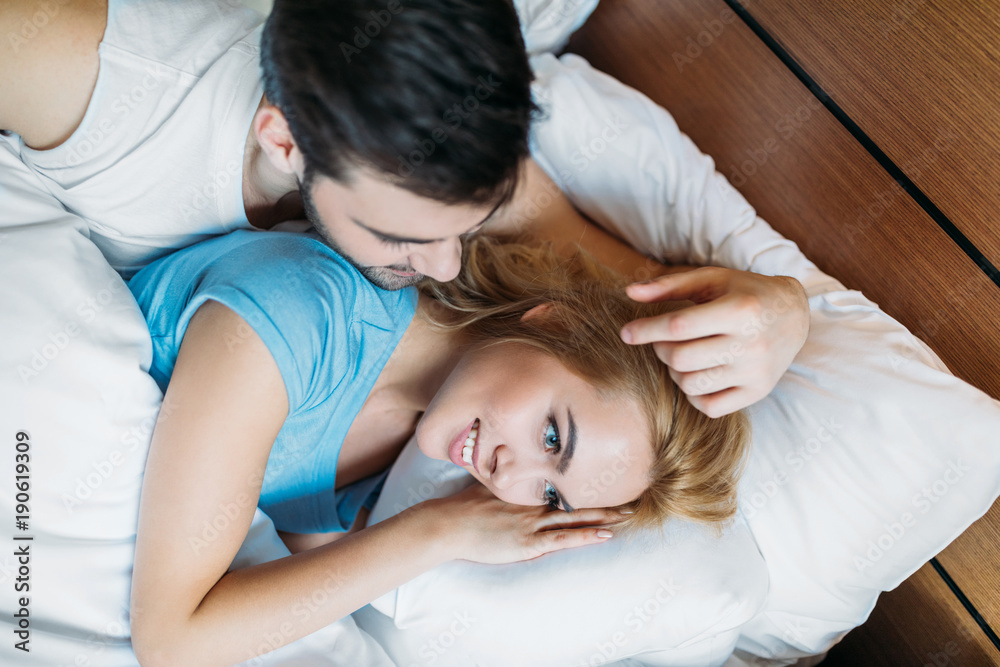 overhead view of boyfriend touching girlfriend hair in bed in morning