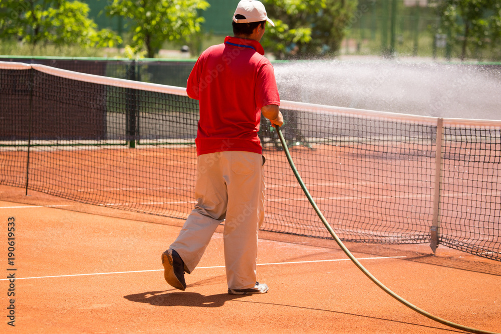 Preparation of a tennis court watering from a hose Stock Photo | Adobe Stock