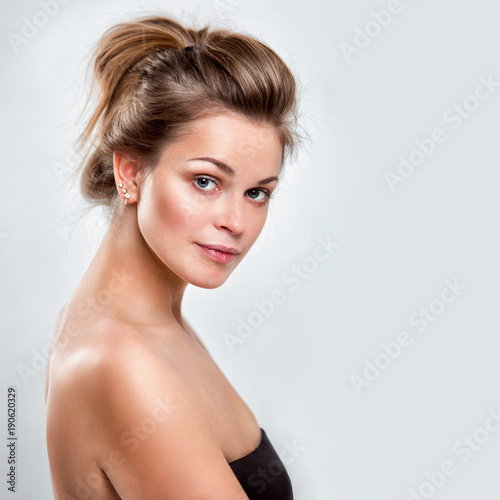 Portrait of a beautiful young smiling woman on a gray background