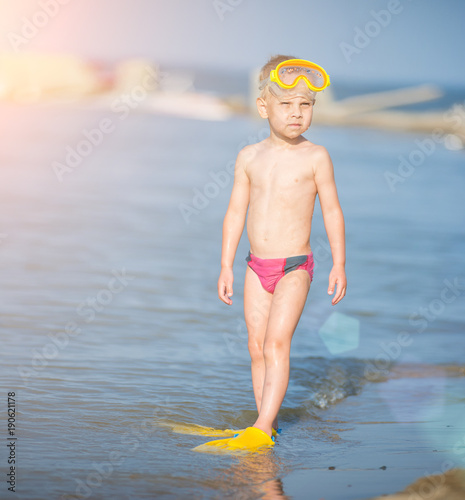 Little boy with snorkel by the sea. Cute little kid wearing mask and flippers for diving at sand tropical beach. Ocean coast.