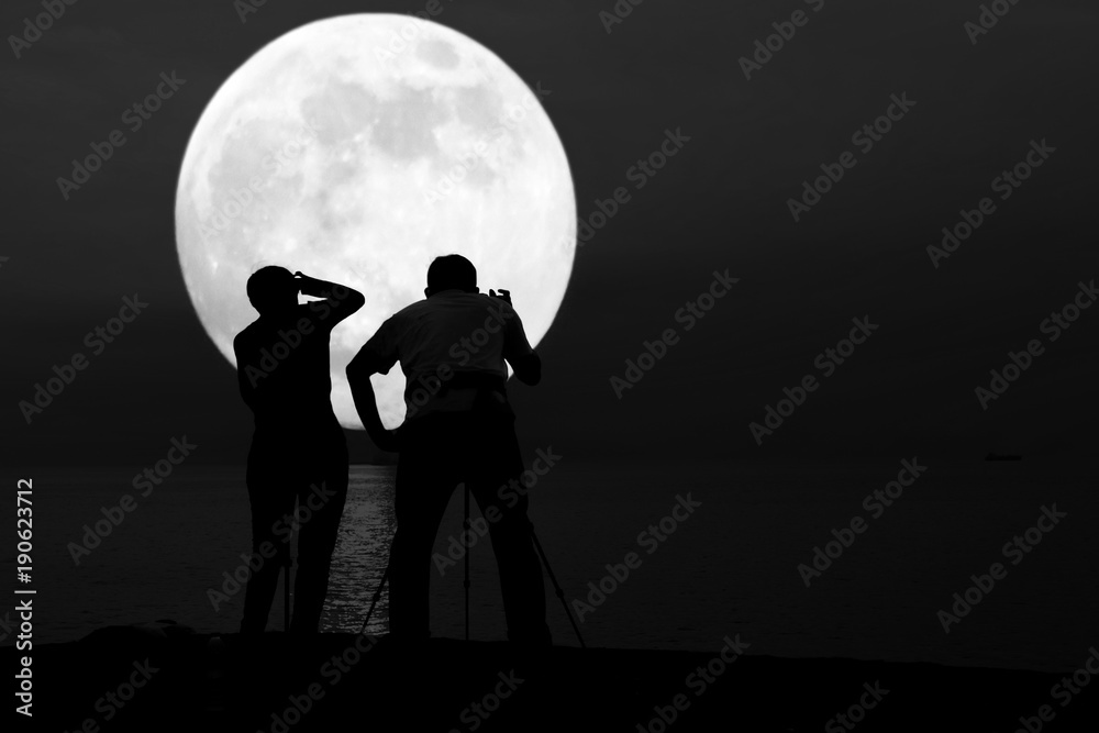 Silhouette of couple taking photo of super blue moon