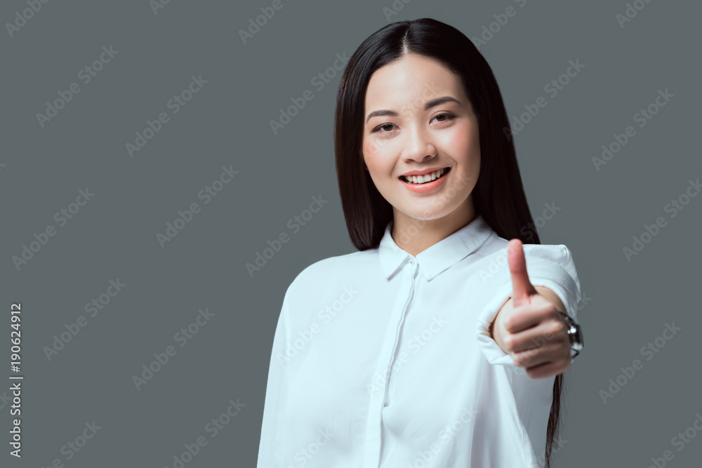 beautiful brunette girl showing thumb up and smiling at camera isolated on grey beautiful brunette girl showing thumb up and smiling at camera isolated on grey