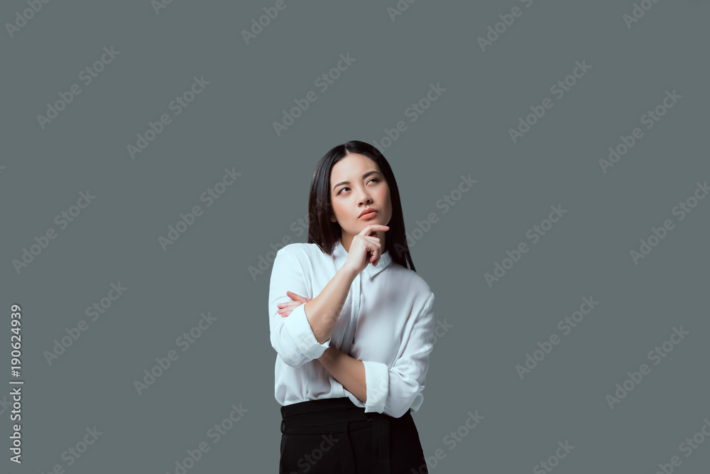 pensive young woman standing with hand on chin and looking away isolated on grey pensive young woman standing with hand on chin and looking away isolated on grey