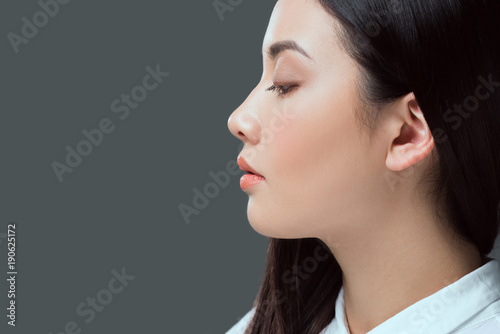 profile portrait of beautiful young asian woman looking away isolated on grey