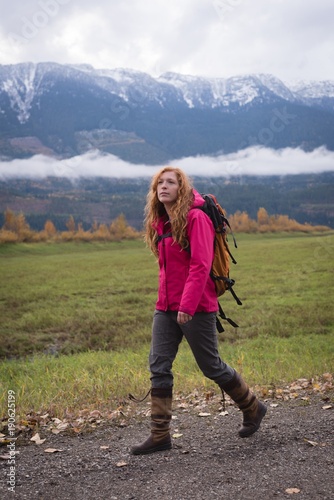 Woman walking on a dirt track against snow clad mountain and photo