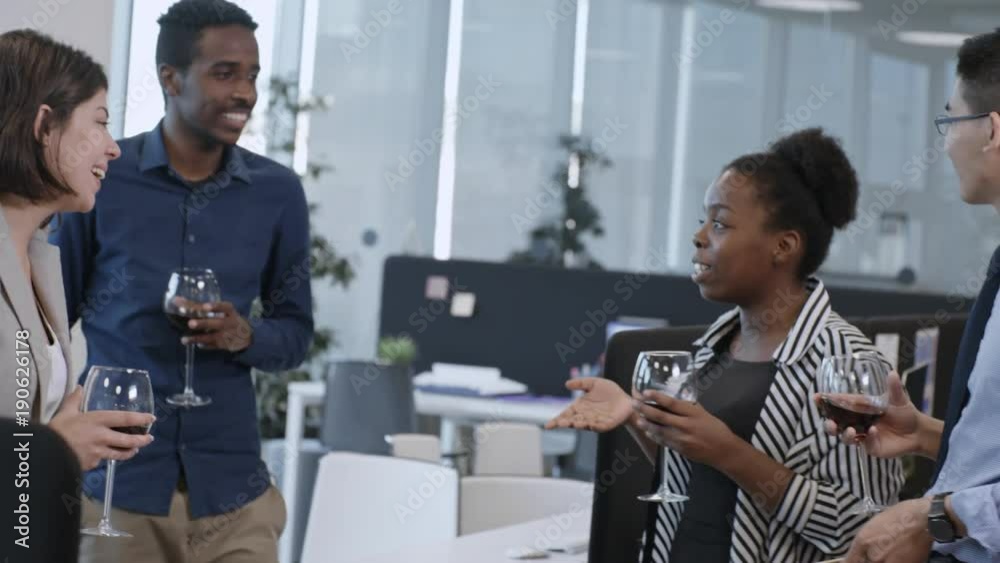 Multinational team of joyful business men and women dancing with wine glasses, toasting, talking and laughing at office party Multinational team of joyful business men and women dancing with wine glasses, toasting, talking and laughing at office party