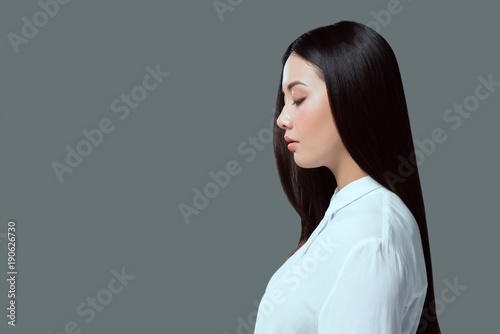 profile portrait of beautiful young asian woman standing isolated on grey photo