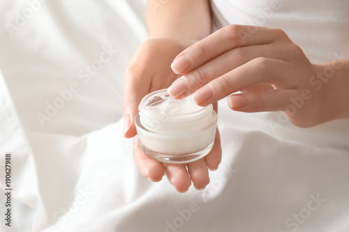 Woman with jar of hand cream at home, closeup