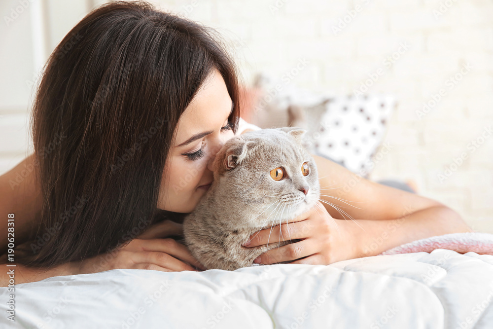 Young woman with cute pet cat on bed at home Young woman with cute pet cat on bed at home