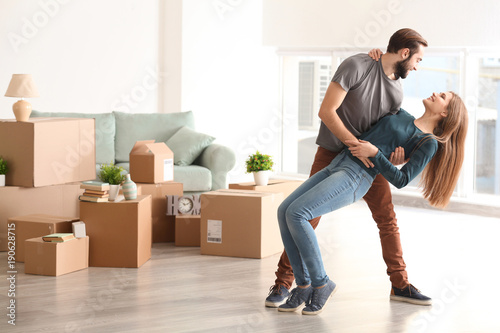 Young happy couple in room with moving boxes at new home © Africa Studio