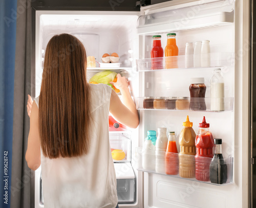 Woman choosing food in refrigerator at home