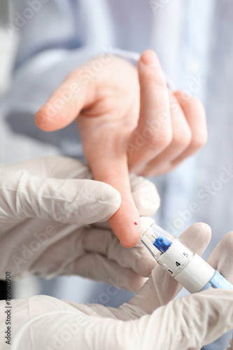Doctor taking patient s blood sample with lancet pen  closeup. Diabetes monitoring