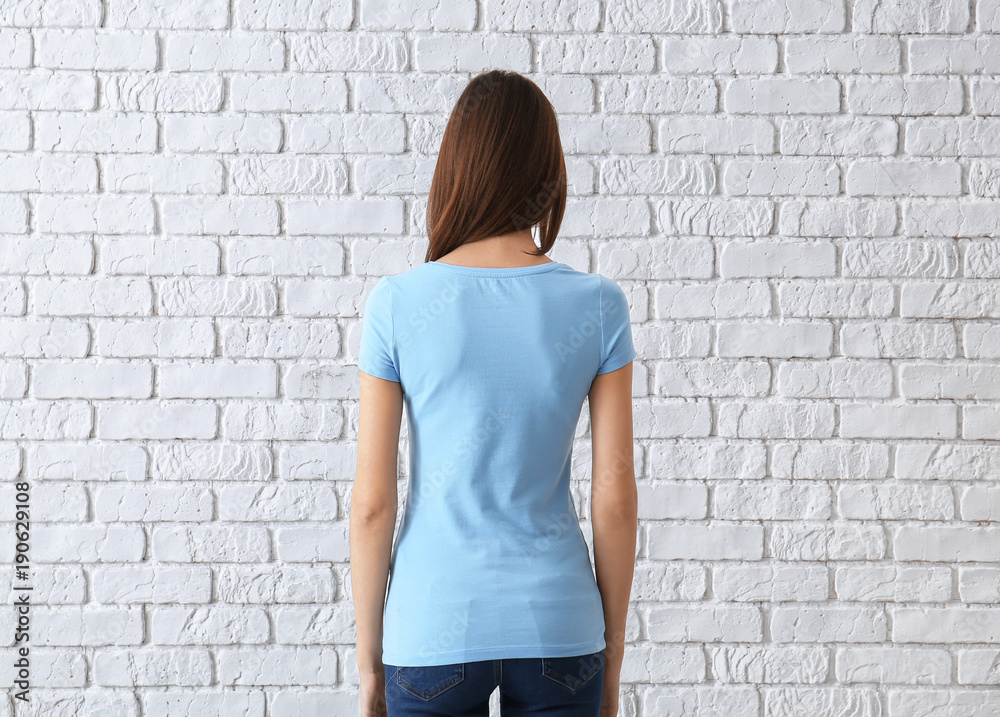 Beautiful young woman in stylish t-shirt near white brick wall. Mockup for design Beautiful young woman in stylish t-shirt near white brick wall. Mockup for design