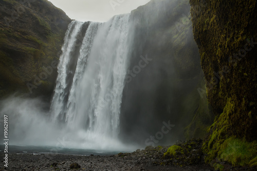 A powerful waterfall among the rocks covered with green moss. Iceland. Dark fabulous atmosphere  vintage.  