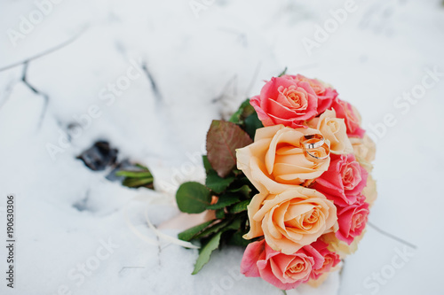 Wedding bouquet with rings at snow.