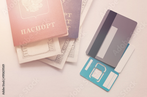 Russian and Belorussian passports, white smartphone, bank card, dollars money are isolated on the white background.