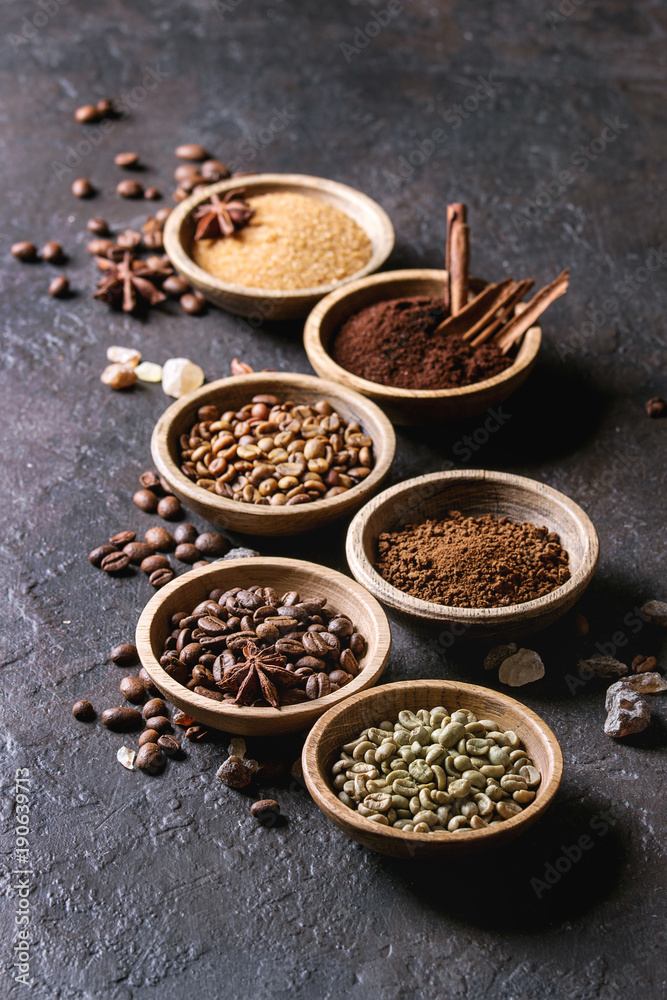 Variety of grounded, instant coffee, different coffee beans, brown sugar, spices in wooden bowls over dark texture background. Copy space Variety of grounded, instant coffee, different coffee beans, brown sugar, spices in wooden bowls over dark texture background. Copy space