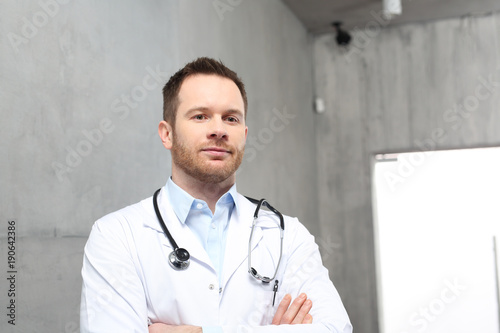 Lekarz. Przystojny lekarz ubrany w biały kitel stoi w klinice