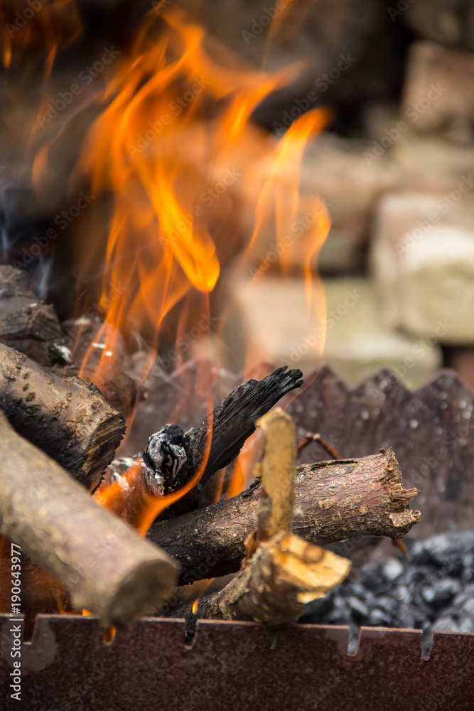 burning logs in a brazier. The flames on the background of the harvested wood burning logs in a brazier. The flames on the background of the harvested wood