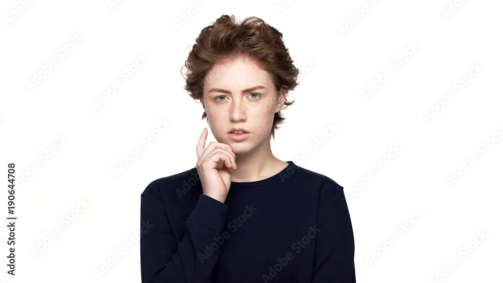 Portrait of focused woman with brown curly hair hesitating and trying to remember or choose over white background. Concept of emotions