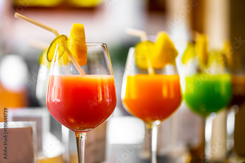 The colorful juice with sliced lime and straw in brandy glasses in restaurant.
