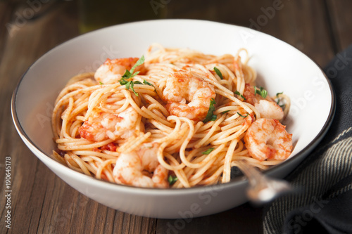 Spaghetti with shrimps, tomato sauce and chopped parsley.