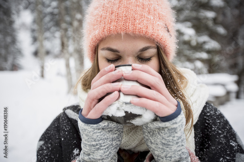 Young woman enjoying hot drink outdoors in winter photo