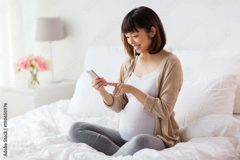 pregnant woman with smartphone in bed at home pregnant woman with smartphone in bed at home