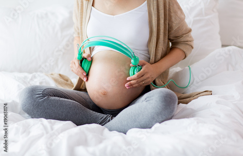 close up of pregnant woman belly with headphones
