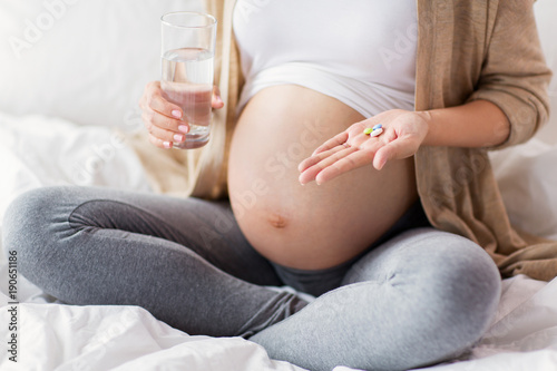 close up of pregnant woman with pills in bed