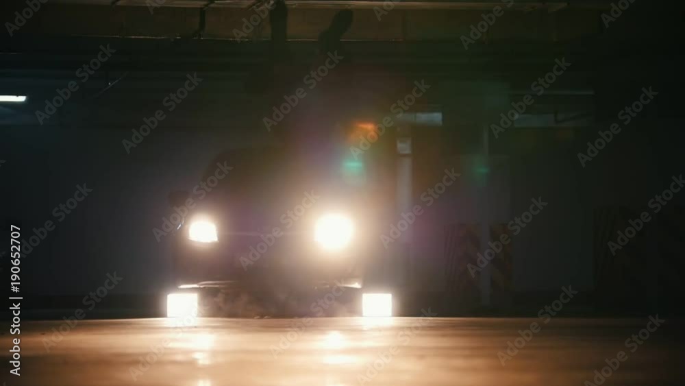 Silhouette of a young stylish guy freerunner doing a series of jumps, flips, and turns in the garage in front of car's headlights - slow-motion Silhouette of a young stylish guy freerunner doing a series of jumps, flips, and turns in the garage in front of car's headlights - slow-motion