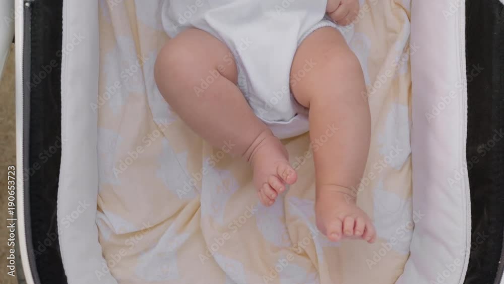 Top view of baby lying in pram and moving little feet and toes