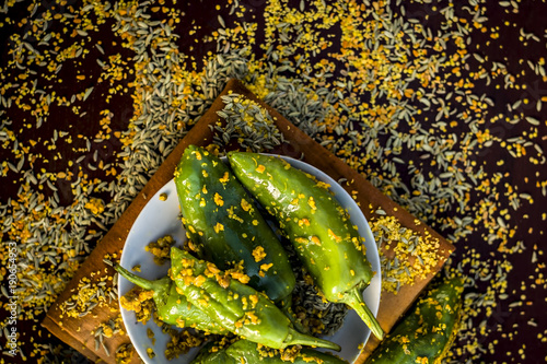 Green chilli pickle marinated in mustard seeds and mustard oil. Dark Gothic style still life concept. photo
