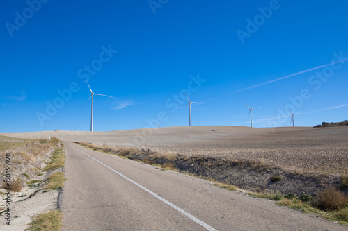 rural road next to wind power turbines on winter meadow near to Ampudia town, in Palencia Spain   © Q