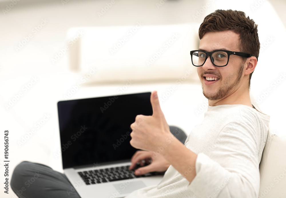 modern young sitting in front of the open laptop and showing thumb up modern young sitting in front of the open laptop and showing thumb up
