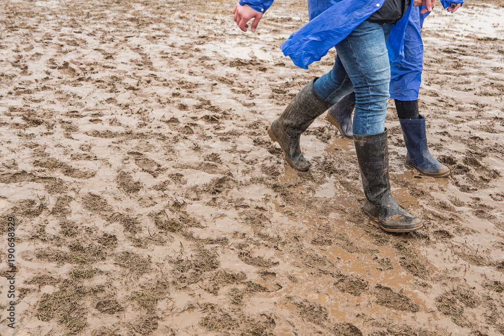 In rubber boots on dirt, at the festival