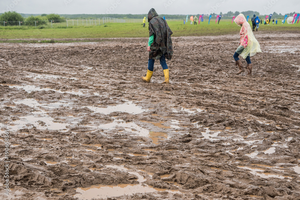In rubber boots on dirt, at the festival