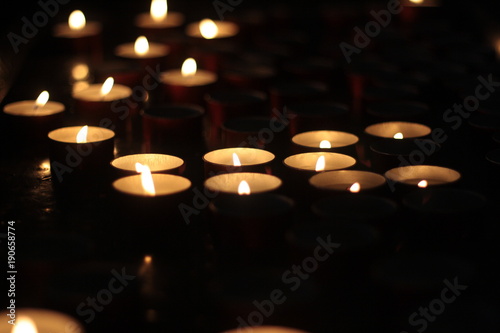 Votive candles glowing in the dark. Close up. Religion and faith icon or background.