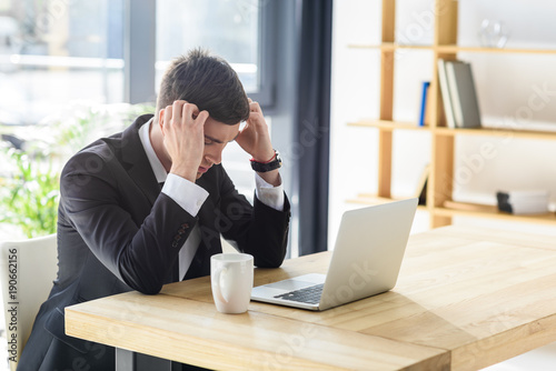 Young businessman suffers from headache while working on laptop © LIGHTFIELD STUDIOS