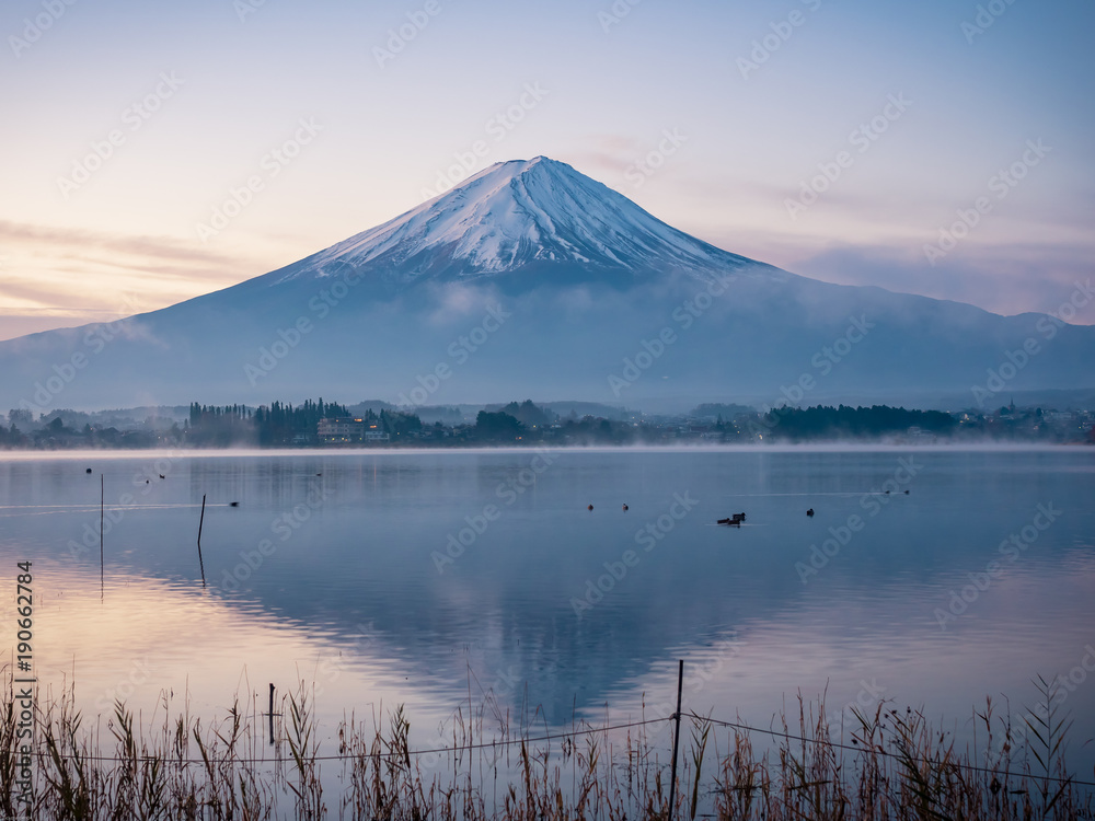 fog with sunrise landscape view from kawaguchi lake with motion blur from group of duck foreground and fuji mountain range background from japan