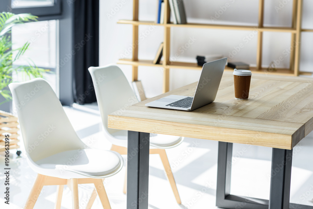 Laptop and coffe cup on table in modern office Laptop and coffe cup on table in modern office