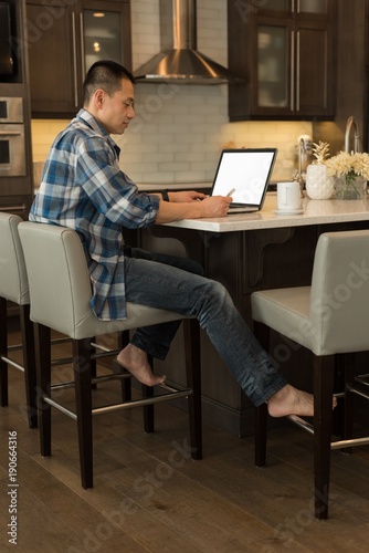 Man using laptop in kitchen photo
