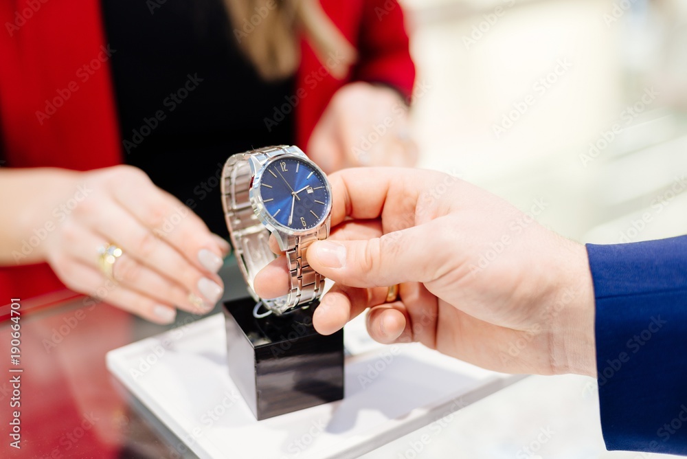 Young elegant man buying wrist watch in jewelry store