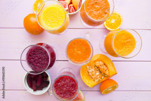 Healthy Food  Diet Concept. Fruit and Vegetable Smoothie assortment with fresh lemos  oranges  beetroot  pumpkin and watermelon on pink wooden background  top view