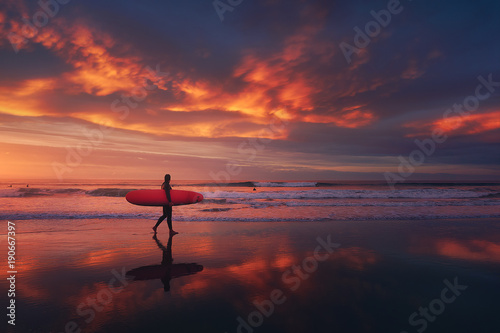 surfer in the beach at sunset with red sky