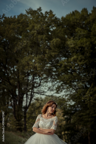 Posing red head sensitive bride wit hthe red lipstick at the forest background. photo