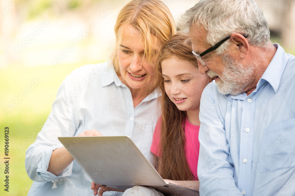 The family is happily sharing a notebook in the garden.Soft focus concept. The family is happily sharing a notebook in the garden.Soft focus concept.